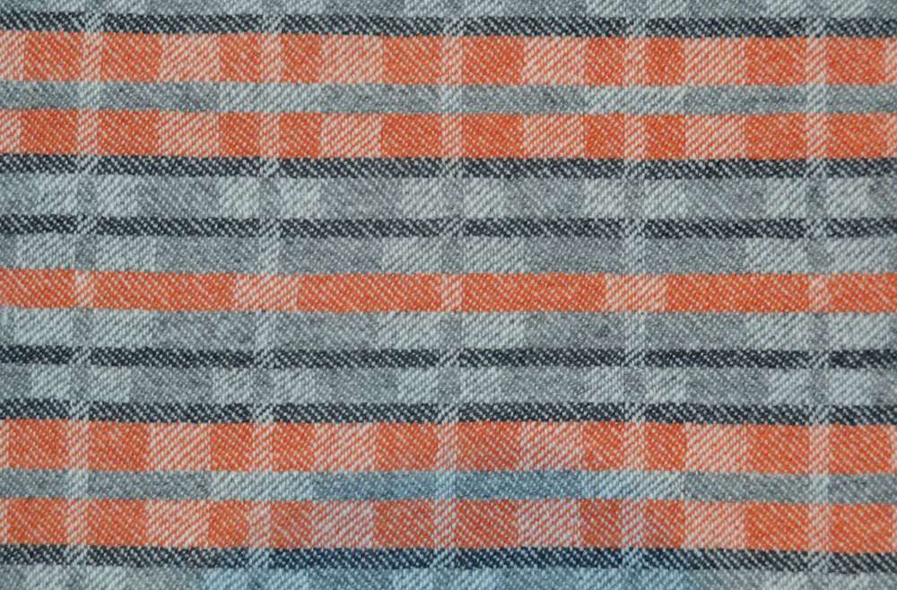 Handwoven 'Dukagang Stripe' lambswool throw in burnt orange and grey - showing reverse dominant colour side