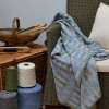 Handwoven 'Lineal' throw in blue, green and grey on chair